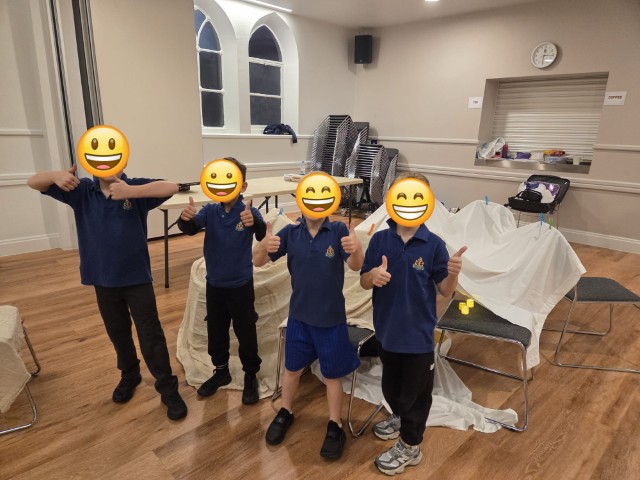 Boys giving a big thumbs up next to the tent they've made - with emojis covering their faces for privacy